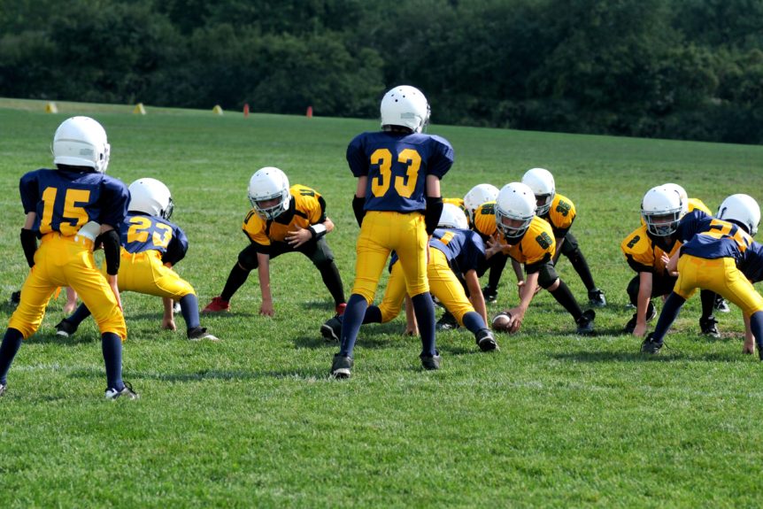 A group of young football players in yellow and blue uniforms.