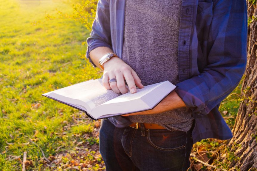 A person holding an open book in their hands.