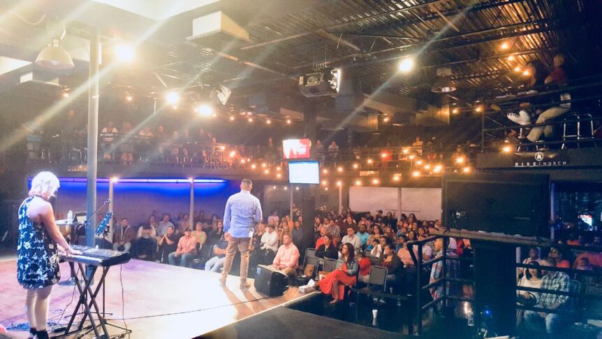 A crowd of people sitting in front of a stage.